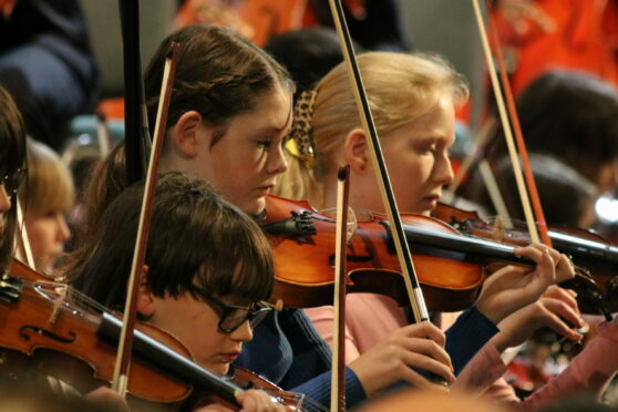 Close Up Of Three Children Playing Violin