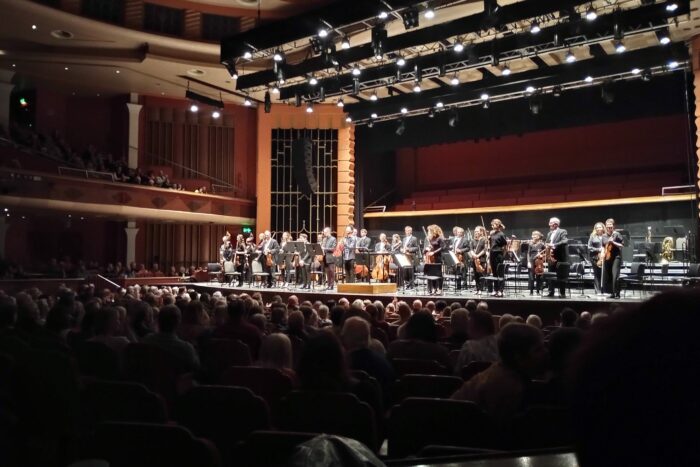An orchestra stands on stage