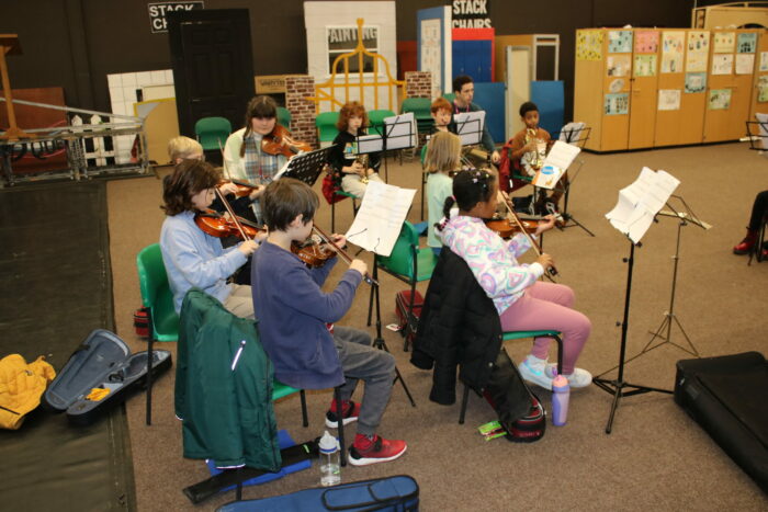 A group of children play music on a variety of instruments