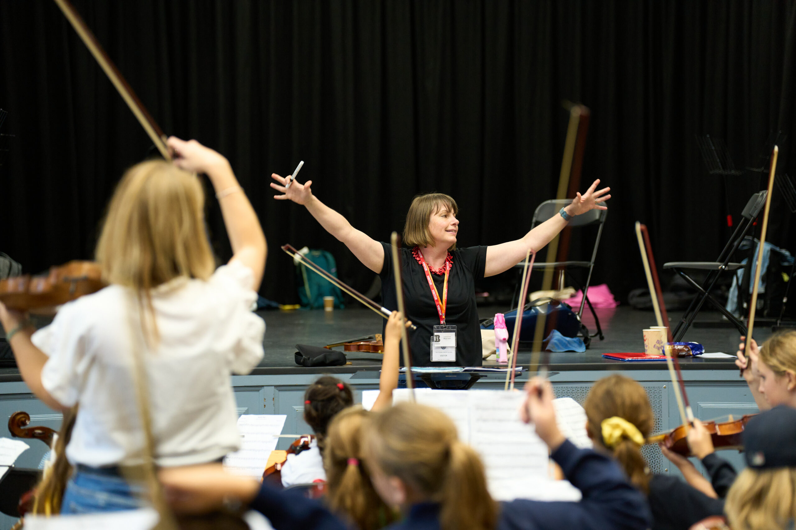 A Woman Conducts Children Playing Stringed Instruments