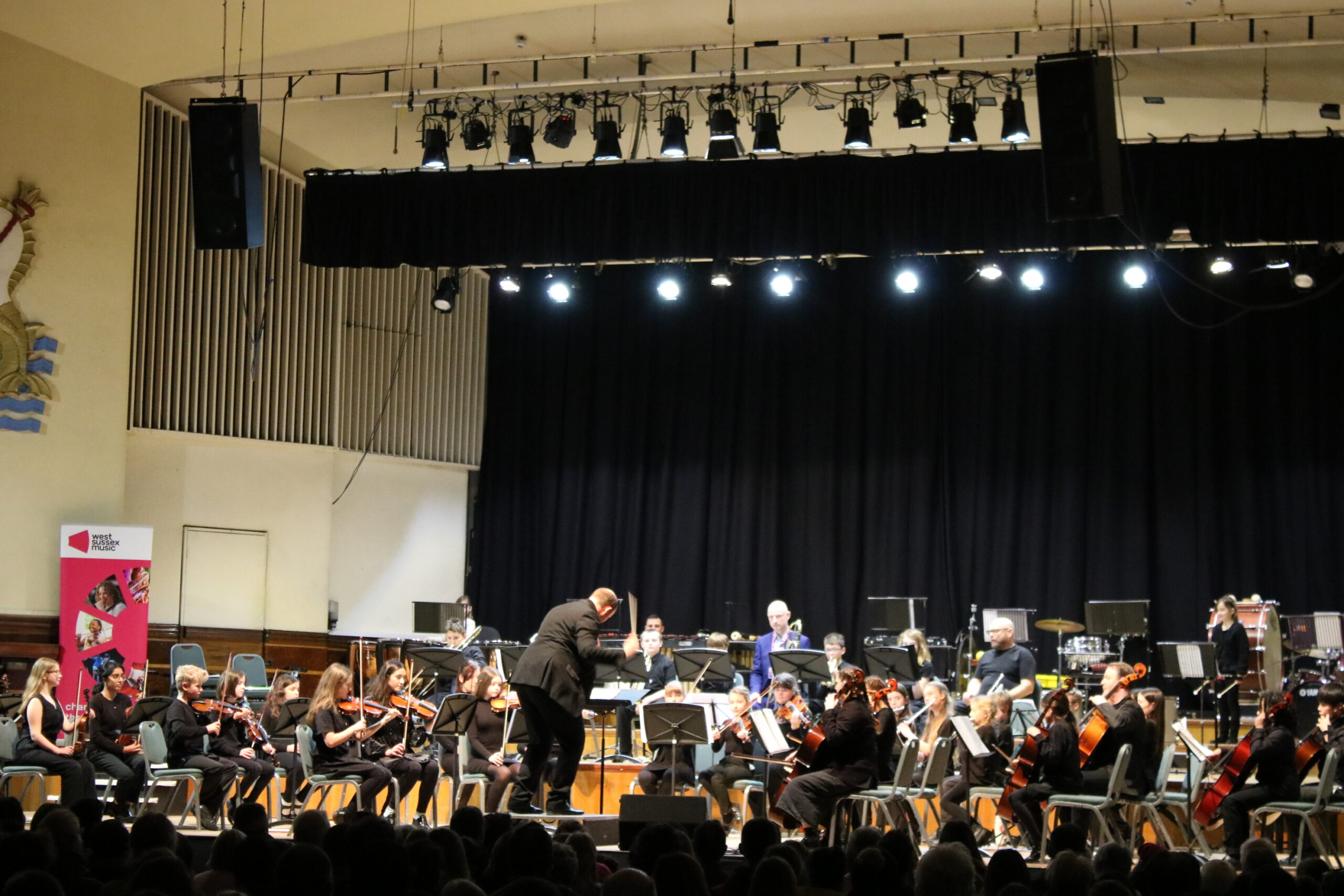 A Group Of Young Musicians Play String Instruments On A Stage