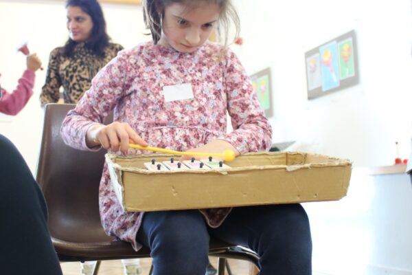 A Girl In A Pink Top Concentrates As She Plays A Xylophone