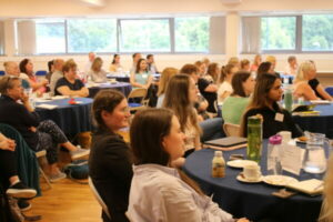A Group Of People Are Sat In A Conference