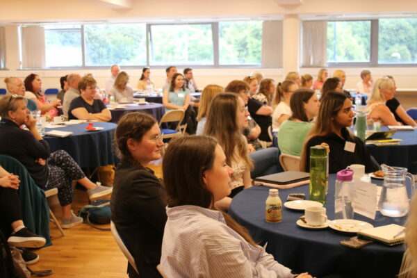 A Group Of People Are Sat In A Conference