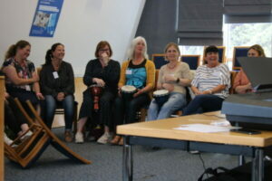 A Group Of Female Teachers Sit In A Row Learning